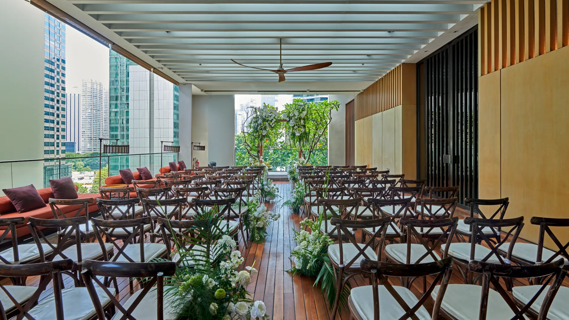 Rooftop wedding ceremony with wooden chairs, floral arch, and Bar counter at The RuMa Hotel and Residences