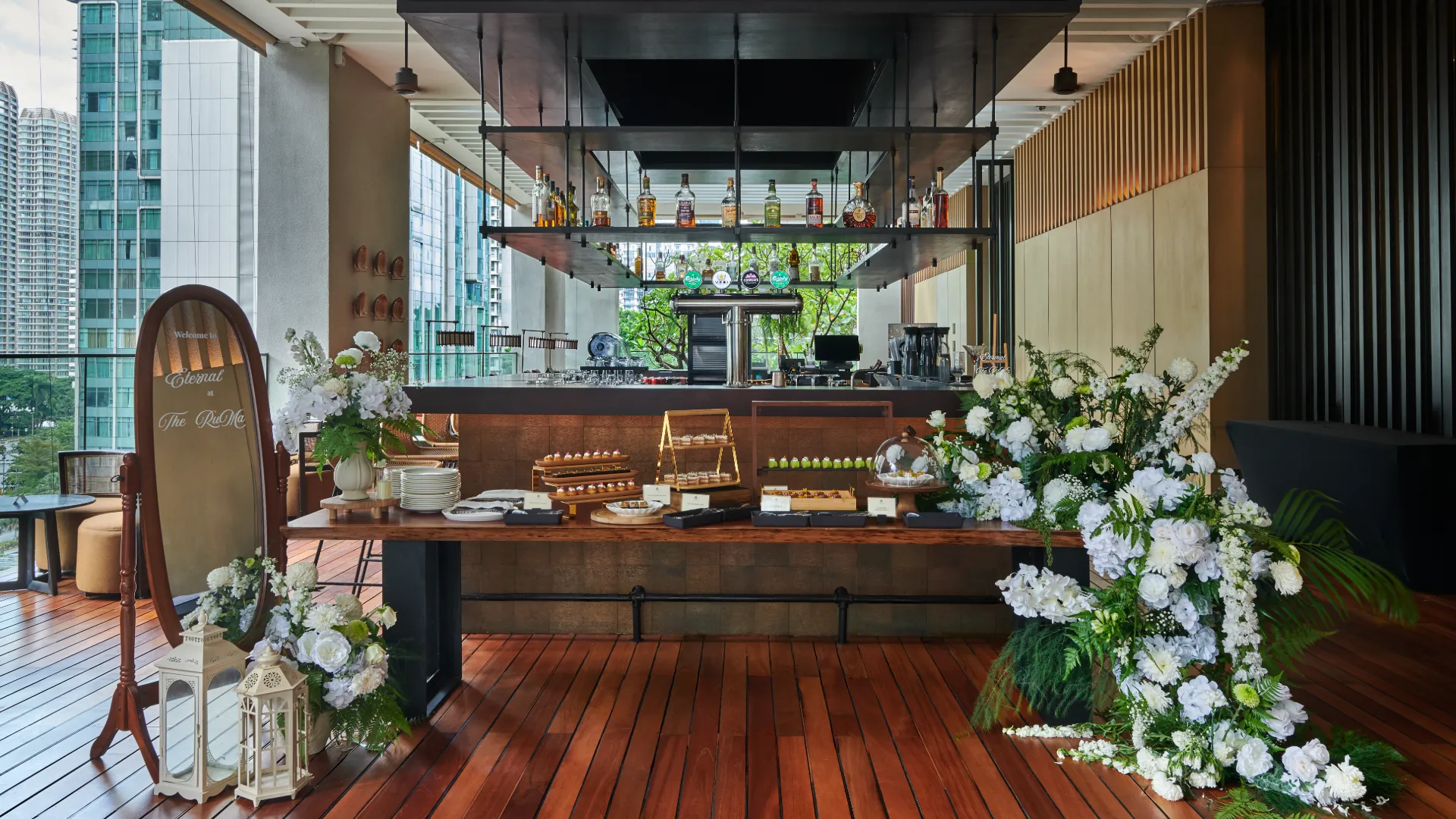 Rooftop wedding ceremony with wooden chairs, floral arch, and Bar counter at The RuMa Hotel and Residences