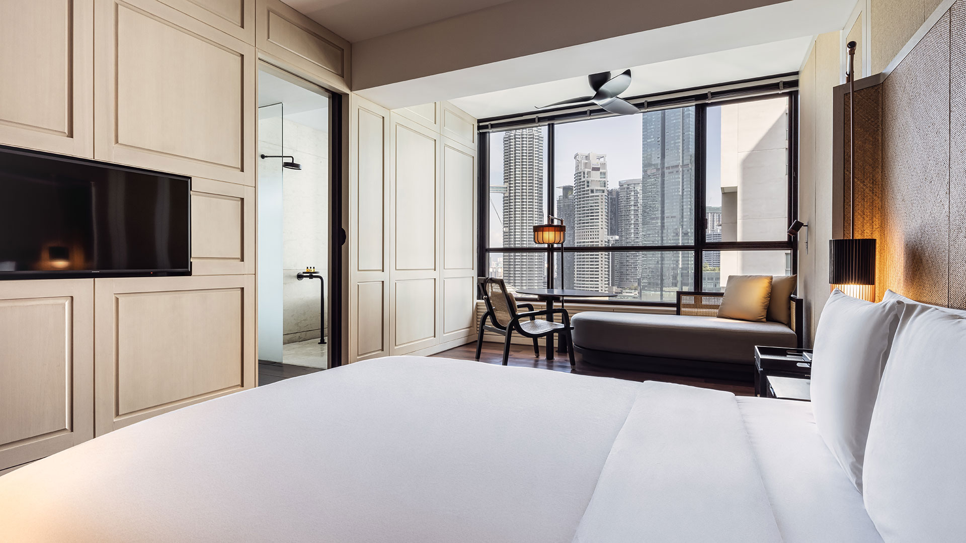 Bed & lounge with a city view in Grand Studio at The RuMa Hotel